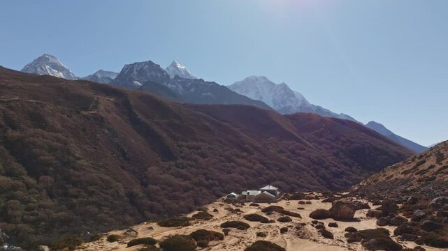 Towering Mount Everest dominating rocky Himalayan terrain in the Shomare to Dingboche Route, highlighting barren landscape and compound building