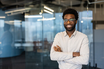 Portrait of a young successful businessman, man smiling looking at camera with crossed arms....