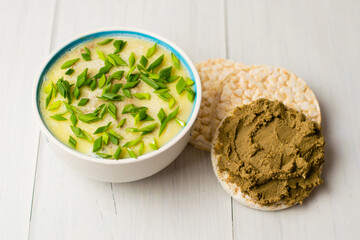 Healthy food, liver pate with butter and green onions in a bowl and beef liver pate on rice bread on a light table
