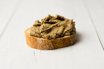 Healthy food, delicious beef liver pate on a baguette with a crispy crust on a light table