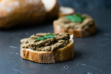 Healthy food, sandwiches with liver pate, parsley and crispy baguette and pieces of baguette on a dark background
