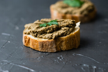 Healthy food, sandwiches with liver pate, parsley and crispy baguette close-up on a dark background