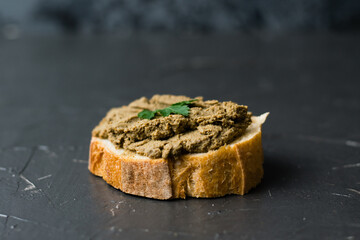 Healthy food, delicious and appetizing sandwich with beef liver, parsley and aromatic baguette with crispy crust close-up on a dark background