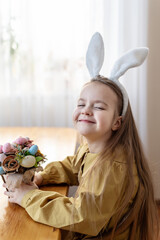 Smiling caucasian young girl with bunny ears holding easter basket indoors