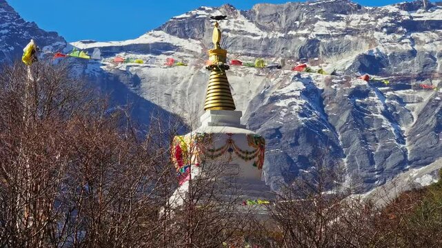 Pristine white stupa crowned with vibrant prayer flags waving against snow capped Himalayan peaks, embodying spiritual tranquility in Namche Bazaar