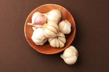 Garlic  Bulb in a wooden bowl.Garlic is a common cooking ingredient with numerous health benefits. Examples include managing cholesterol, boosting heart health, supporting the immune system, protectin