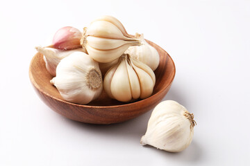 Garlic  Bulb in a wooden bowl.Garlic is a common cooking ingredient with numerous health benefits. Examples include managing cholesterol, boosting heart health, supporting the immune system, protectin