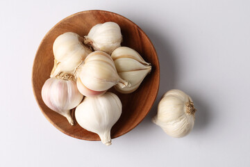Garlic  Bulb in a wooden bowl.Garlic is a common cooking ingredient with numerous health benefits. Examples include managing cholesterol, boosting heart health, supporting the immune system, protectin