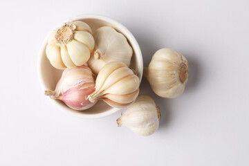 Garlic  Bulb in a ceramic bowl.Garlic is a common cooking ingredient with health benefits. Examples include managing cholesterol, boosting heart health, supporting the immune system, protectin