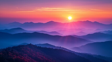 Obraz premium Vibrant sunset over layered, hazy mountains.