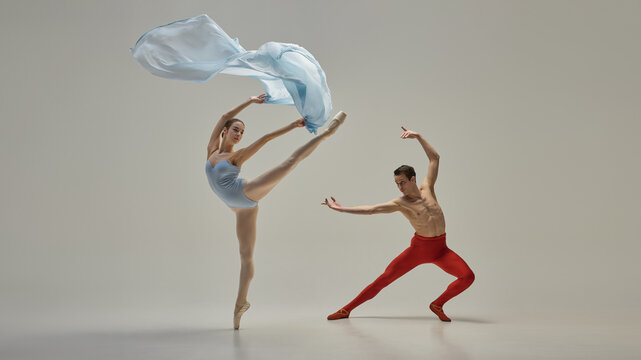 Young artistic ballet dancers performing dynamic pose with fluid and expressive movement against minimal background. Concept of grace, beauty, balance, partnership, rhythm, elegance, motion.