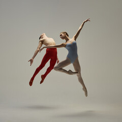 Naklejka premium Elegant ballet moment captured mid-movement, highlighting form, control, and expressive artistry against white studio background. Concept of ballet and art, line, technique, performance.