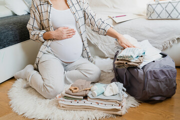 Pregnant woman is packing suitcase for maternity hospital getting ready for childbirth.