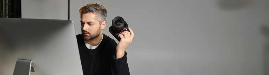 Fototapeta premium Creative professional immersed in editing work while holding a camera indoors