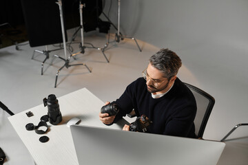Creative professional examining camera equipment in a well lit studio workspace