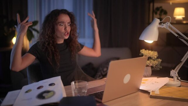 Frustrated young woman typing on a laptop at night. She struggles with coding, gets angry, swears, and gestures in frustration, showing stress and disappointment in her home office