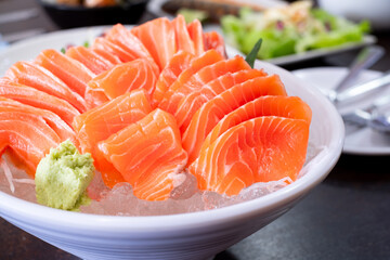 Raw salmon slice or salmon sashimi and wasabi in Japanese style fresh serve on ice in white bowl. Japanese traditional food or with low calories and high nutrition and healthy diet dish.