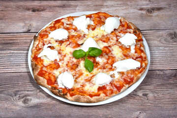Pizza margherita called bufalina with tomato buffalo mozzarella and basil in a plate isolated on wooden background
