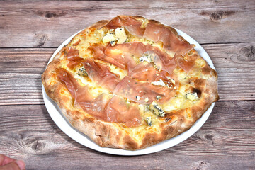 talian Pizza whit gorgonzola cheese and Tyrolean speck ham in a plate isolated on wooden background