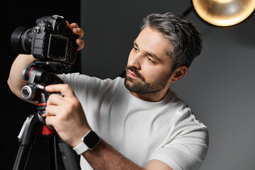 Professional photographer adjusting camera settings in modern studio environment