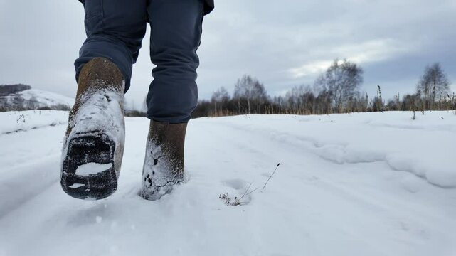 close-up of a man's legs in felt boots, a man walks through snowdrifts in Siberia