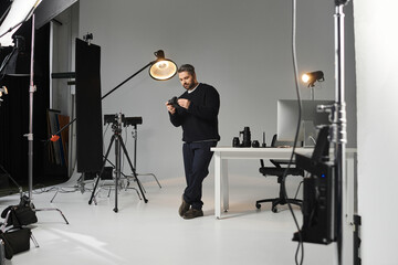 Creative man engages with camera equipment in modern studio setting for professional work