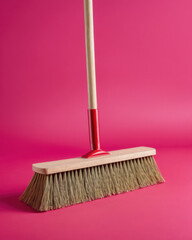 Broom closeup in studio room with red backdrop, offering a unique abstract feel.