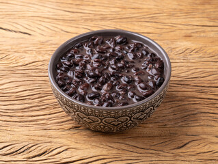 Cooked black beans in a bowl over wooden table
