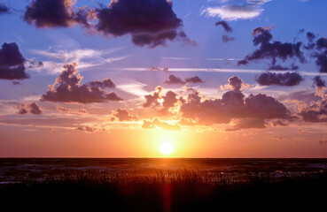 Vibrant sunset illuminating clouds over a tranquil landscape