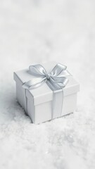 A small white gift box tied with a elegant silver ribbon on a snowy white background, winter, white gift box