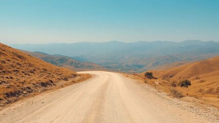 Winding Dirt Road Through Dry Hills Towards Distant Town Under Bright Sky