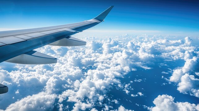 A close-up of an airplane wing cutting through clouds with the deep blue of the Atlantic Ocean visible far below during a transatlantic flight.