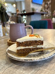 A piece of carrot cake and cup of tea in cafe. Vertical. Carrot cake