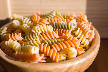 Italian pasta fusilli in a wooden bowl on a table.