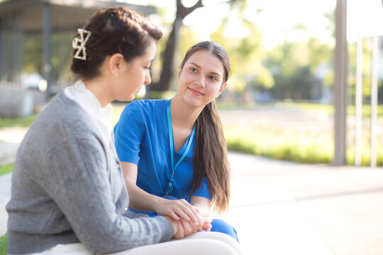Young caucasian nurse concerned and comforting with sad patient in outdoor park, doctor woman support and counseling with patient, caregiver and service with senior, medical and consoling.