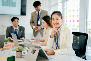 Fototapeta premium Woman in a white jacket is smiling at the camera in front of a group of people
