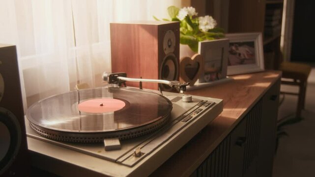 Close-up no people shot of turntable with record, loudspeakers and picture frames on top of wooden dresser in living room
