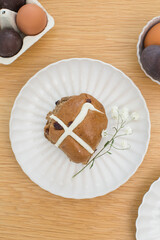 Hot cross buns on white plate on wooden table. Happy Easter