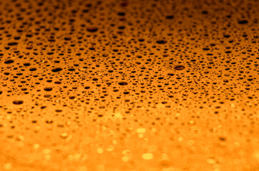 Rain droplets on a dark golden color background with customizable space for text or ideas