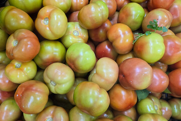 Close-up of fresh green and red tomatoes displayed at a local market, showcasing natural produce and healthy eating options.