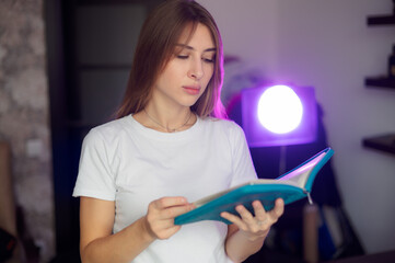Young woman reading book while lounging comfortably on soft home sofa, experiencing quiet personal...