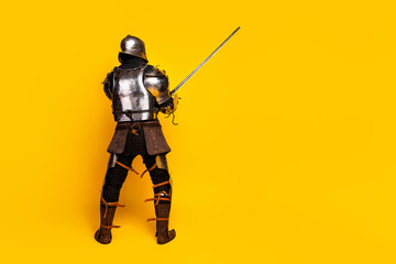 Knight in medieval armor brandishing a sword on a bold yellow background
