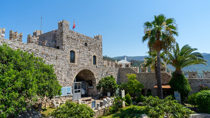 Obraz premium Marmaris Castle and Archaeology Museum, сourtyard and fortress walls, huge historic landmark in Marmaris, Turkey. Turkish flag