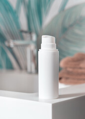 White cream bottle near brown folded towels on basin in tropical bathroom close up, cosmetic mockup