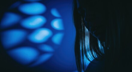 Silhouette of a woman with blue light patterns creating a moody atmosphere