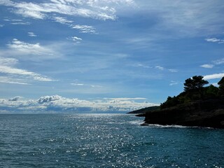 Beautiful sea blue shiny waters, rocky coastline and amazing sky clouds.