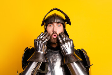 Surprised knight in medieval armor posing on vibrant yellow background