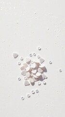 A scattering of shimmering scales rests on an elegant pearl white background with subtle texture and shimmering effect, beachy, oceanic