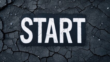Bold white 'START' text on cracked asphalt surface, conveying a sense of beginning and opportunity