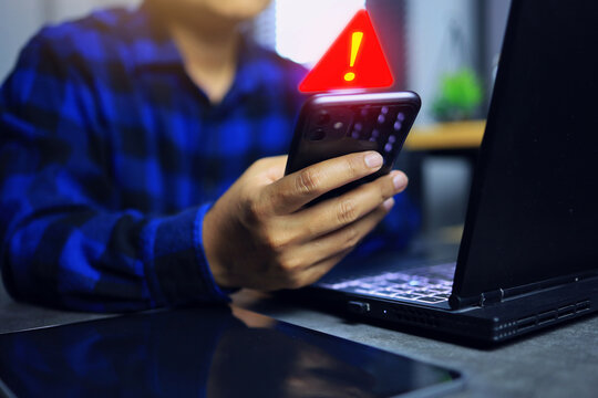 A man is reading a message on a smartphone screen and an icon alerts him of an unusual situation such as a thief accessing his financial data or hacking.
